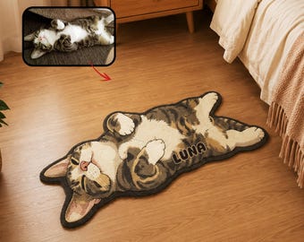 May include: A custom-shaped area rug featuring a brown, white, and gray tabby cat lying on its back with its paws curled. The rug has a dark border and the name LUNA embroidered in dark letters on the cat's side, matching a reference photo.