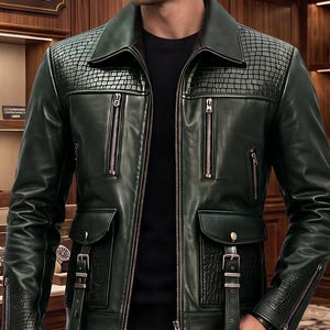 May include: A dark green leather jacket featuring a crocodile-textured pattern on the shoulders and sleeves, a pointed collar, vertical zippered chest pockets, and two lower flap pockets with buckle straps, worn over a plain black shirt.