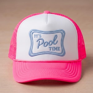 May include: A neon pink and white trucker hat featuring a mesh back and a solid front panel. The front displays an embroidered light blue rectangular frame with rounded corners containing the text IT'S Pool TIME in a mix of script and block fonts.
