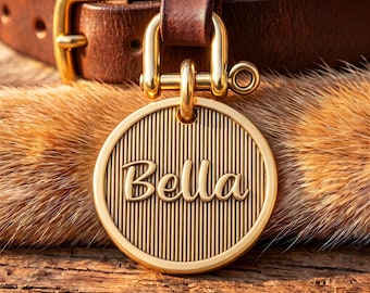 Op de afbeelding: Een ronde, goudkleurige metalen naamplaatje voor huisdieren met een verticale ribbelstructuur en de naam Bella in een sierlijk lettertype. Het plaatje is bevestigd aan een bruine leren halsband met een goudkleurige gesp en hardware.