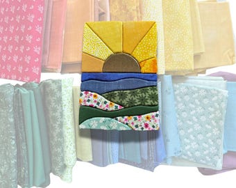 May include: A rectangular fabric art piece featuring a sun rising over a landscape of rolling hills and floral patterns, layered over a collection of folded fabric swatches in various shades of pink, yellow, blue, green, and white.