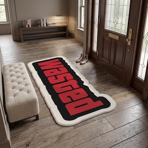 Puede incluir: Una alfombra rectangular con borde blanco, fondo negro y la palabra "Wasted" impresa en letras mayúsculas rojas y llamativas. La alfombra está colocada sobre un suelo de madera, mostrando un diseño de alto contraste con tipografía nítida.