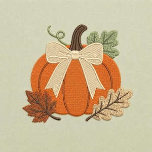 May include: An orange pumpkin machine embroidery design featuring a dark brown stem, a cream-colored ribbon bow tied around the top, and three detailed leaves in shades of green and brown, all stitched onto a light sage green fabric background.