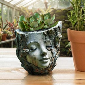 May include: A gray, textured planter shaped like a tree trunk with a sculpted human face featuring closed eyes and a serene expression. The planter contains a green succulent plant with rounded leaves, showcasing a detailed bark-like exterior.