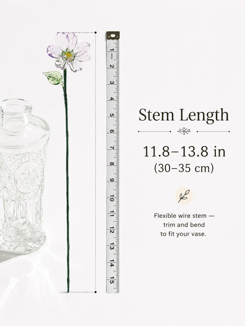 May include: A glass flower with translucent white and purple petals, a yellow center, and a green leaf on a thin, flexible wire stem. A measuring tape shows a stem length of 11.8 to 13.8 inches. Text reads: Stem Length 11.8&ndash;13.8 in (30&ndash;35 cm).