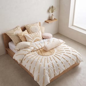 May include: A white bedding set featuring a tufted sunburst pattern in beige. The set includes a duvet cover, several square throw pillows with fringe and sun motifs, a rectangular lumbar pillow, and a cylindrical bolster pillow in cream.