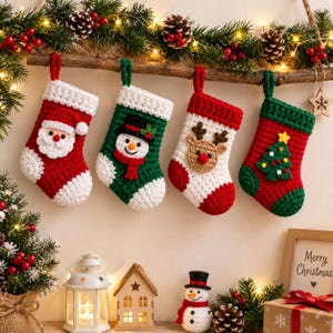 Puede incluir: Cuatro calcetines navideños de ganchillo colgados de una rama de madera. El primero es rojo con una cara de Papá Noel, el segundo es verde con un muñeco de nieve, el tercero es blanco con un reno y el cuarto es verde con un diseño de árbol.