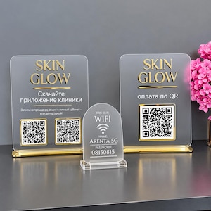 May include: Three clear acrylic signs with gold accents. Two rectangular signs feature the text SKIN GLOW, QR codes, and Russian text. The smaller arched sign displays JOIN OUR WIFI, the name ARENTA 5G, and the password 08150815 in white text.