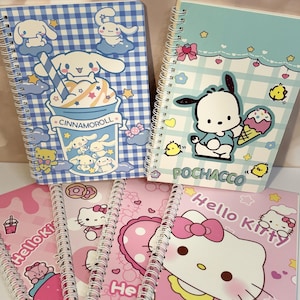 May include: A collection of four spiral-bound notebooks featuring Sanrio characters. One notebook displays Cinnamoroll with a blue gingham pattern, another shows Pochacco with ice cream, and two notebooks feature Hello Kitty in pink designs.