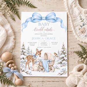 Op de afbeelding: Een rechthoekige uitnodigingskaart voor een babyshower met een grote lichtblauwe strik bovenaan. De tekst luidt: BABY it's cold outside, JOIN US FOR A BABY SHOWER HONOURING JESSICA GRACE, WINTER COTTAGE, FERN LANE, OXFORD, SATURDAY DECEMBER 14TH AT 2 O'CLOCK, RSVP SARAH 1234567890, REGISTERED AT BABY BOUTIQUE. Daaronder staat een illustratie van een reekalf en een konijn naast een vintage kinderwagen in een besneeuwd bos.