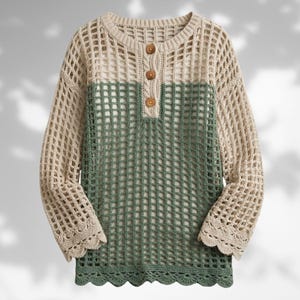 Könnte beinhalten: Ein langärmeliger Häkelpullover mit einem Color-Block-Design, bestehend aus einem beigen Oberteil und einem salbeigrünen Unterteil. Das Kleidungsstück hat einen Rundhalsausschnitt, drei braune Knöpfe an der Knopfleiste und gewellte Säume.