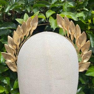 Op de afbeelding: Gouden blad kroon haarband met een eenvoudig ontwerp. De haarband is gemaakt van metaal en heeft aan elke kant een rij gouden bladeren.