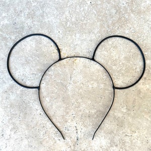 Puede incluir: Diadema de metal negro con dos orejas circulares grandes, que se asemejan a las orejas de Mickey Mouse.