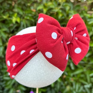 May include: Red headband with white polka dots, tied in a bow. The headband is made of soft fabric and is perfect for adding a touch of style to any outfit.
