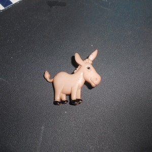 May include: A small, pink plastic donkey figurine with black hooves.
