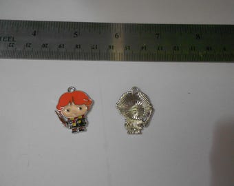 Op de afbeelding: Twee metalen bedels met een stripfiguur met rood haar, een toverstaf en een schooluniform. De bedels zijn ongeveer 2,5 cm hoog. Eén bedel toont de voorkant, de andere de achterkant.