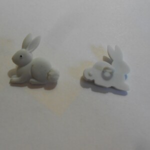 May include: Two white plastic bunny buttons. One button shows the front of the bunny, the other shows the back.