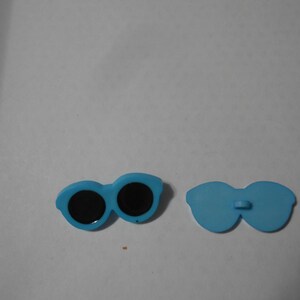 May include: Two blue plastic sunglasses, one pair with black lenses and the other pair without lenses.