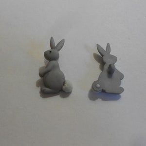 Può includere: Due bottoni di plastica grigi a forma di coniglio con code bianche e soffici. I bottoni misurano circa 2,5 cm.