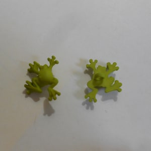 以下が含まれることがあります： 緑色のカエルの形をしたボタンが2つ。ボタンはプラスチック製で、滑らかでマットな仕上がりです。