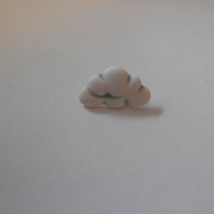 Puede incluir: Botón de plástico blanco con forma de nube y contornos grises.
