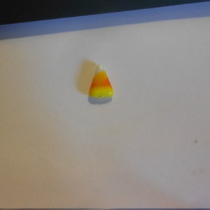 Puede incluir: Un pequeño amuleto de maíz dulce, blanco, amarillo y naranja.