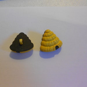 May include: Two beehive-shaped buttons, one black and one yellow. The black button has a loop on the back for sewing.