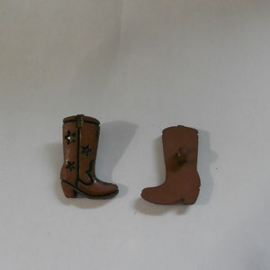 May include: Two brown cowboy boot buttons with a star design. The buttons are about 1 inch tall.