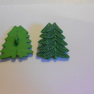 Könnte beinhalten: Zwei grüne Weihnachtsbaum-Knöpfe aus Kunststoff. Ein Knopf ist flach und der andere hat ein strukturiertes Design.