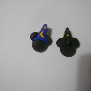 Könnte beinhalten: Ein Paar schwarze Mickey-Mouse-Ohren aus Gummi mit einem blauen und gelben Zaubererhut auf einem Ohr. Das andere Ohr hat einen gelben Stern auf der Rückseite.