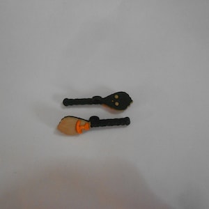 May include: Two black and orange plastic broomsticks. The broomsticks are about 4 inches long.