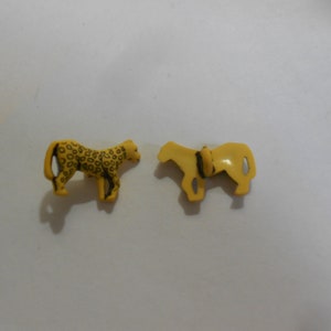 May include: Two yellow plastic animal figurines. One is a leopard with black spots and the other is a horse.