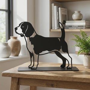 Könnte beinhalten: Eine schwarz-weiße Metallskulptur, die die Silhouette eines Beagles im Profil zeigt. Der Hund hat ein weißes Gesicht, eine weiße Brust und weiße Pfoten, während der Körper und die Ohren schwarz sind. Er steht auf einem flachen, rechteckigen Metallsockel.