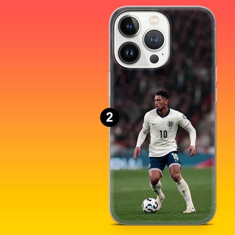 Puede incluir: Una funda transparente para smartphone con la imagen impresa de un futbolista que viste una camiseta blanca de Inglaterra con el n&uacute;mero 10, pantalones cortos azul oscuro y calcetines blancos, regateando un bal&oacute;n en un campo verde.