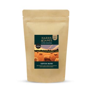 May include: A tan paper coffee pouch featuring a dark green label with the text Harris & James Coffee Roasters, Suffolk Blend, and 100% Arabica. The label displays an illustration of a golden hay field with round hay bales under a sunset sky.