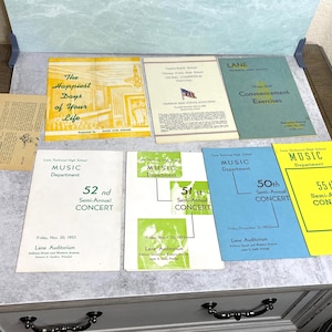 May include: A collection of vintage event programs and publications, including concert announcements and commencement exercises. The items feature text and graphics in various colors, such as yellow, green, and blue, and are arranged on a light surface.