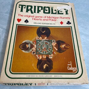 May include: A rectangular board game box for Tripoley, the original game of Michigan Rummy, Hearts and Poker, Deluxe Edition No. 111. The box features a central illustration of three people playing the game around a table, with card suit icons.
