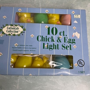 May include: A light blue box with a clear window displaying a set of Easter lights. The lights are shaped like yellow chicks and colored eggs. The box reads "10 ct. Chick & Egg Light Set" and "Total length approx 10 feet."