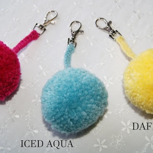 Puede incluir: Tres llaveros de pompón en rosa intenso, aqua helado y amarillo narciso. Cada llavero tiene un anillo de metal plateado y un cierre de metal plateado.