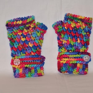 May include: A pair of colorful, crocheted fingerless gloves. The gloves feature a vibrant mix of rainbow colors, including red, blue, yellow, and purple. Each glove has a cuff with a decorative button. The gloves are designed to keep hands warm while leaving fingers free.