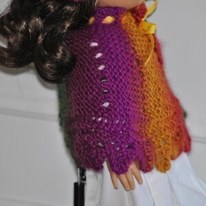 May include: A purple, green, and orange knitted sweater with a yellow ribbon. The sweater has a lacy pattern and is made with a soft yarn.