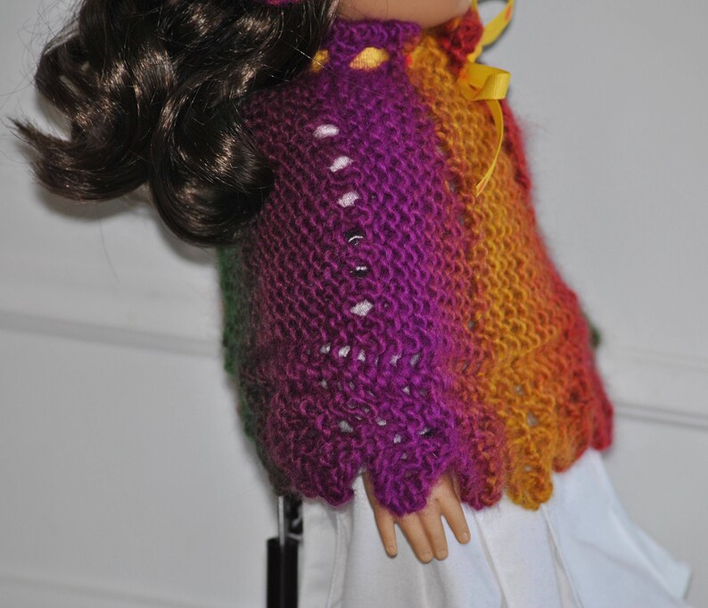 May include: A purple, green, and orange knitted sweater with a yellow ribbon. The sweater has a lacy pattern and is made with a soft yarn.