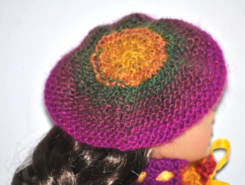 May include: A purple, green, and yellow knitted hat with a crocheted flower design.