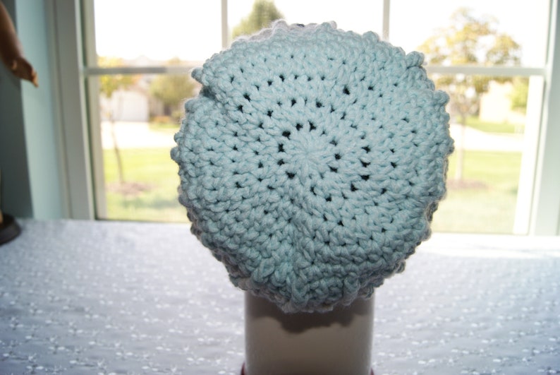 May include: A light blue crocheted beanie hat with a textured pattern.