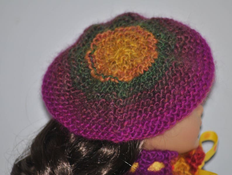 May include: A pink, green, and yellow knitted hat with a flower design. The hat is made of soft yarn and has a comfortable fit.