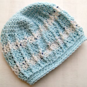 May include: A blue and white crocheted beanie hat. The hat is made with a textured stitch and has a striped pattern.