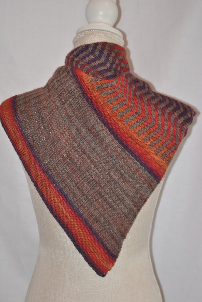 Puede incluir: Una bufanda de punto triangular con un patr&oacute;n de chevron en tonos de marr&oacute;n, naranja y morado.