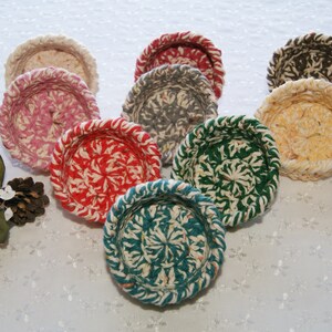 May include: A collection of nine small crocheted baskets in various colors, including pink, red, green, blue, yellow, and brown. The baskets are all round and have a decorative pattern.