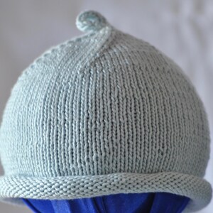 May include: A light blue knitted hat with a pointed top and a folded brim.