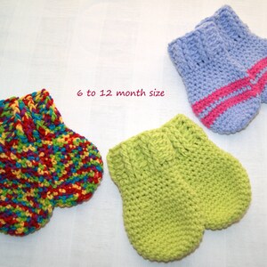 May include: Three pairs of knitted baby mittens in different colors and patterns. The mittens are 6 to 12 month size. One pair is green, one pair is multi-colored, and one pair is light blue with pink stripes.